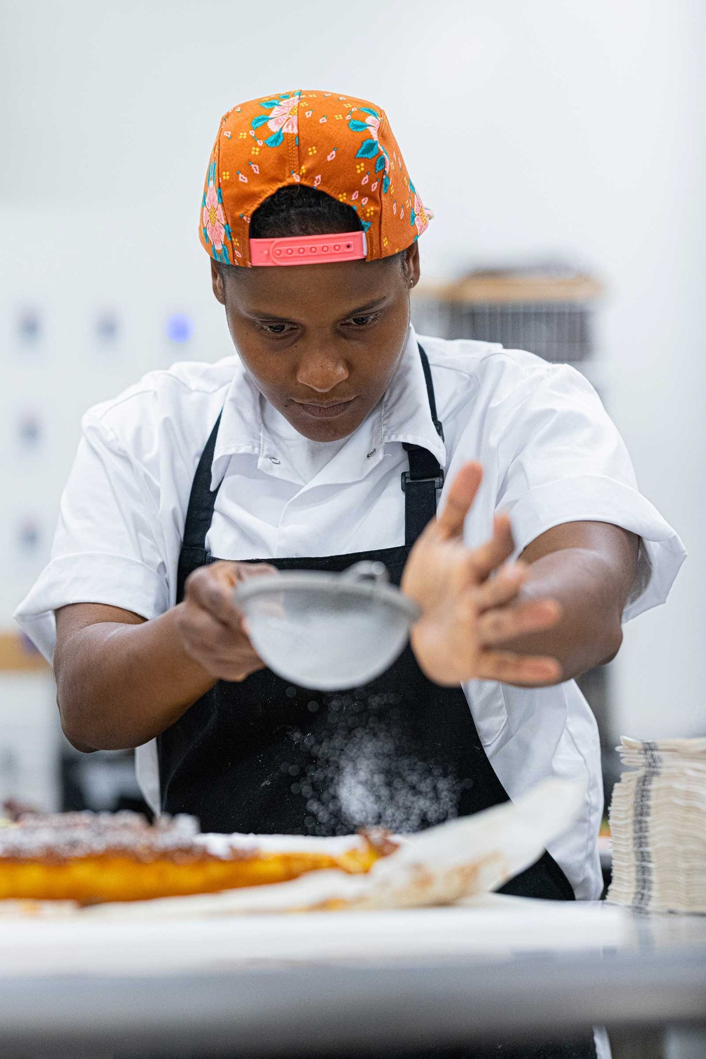 Chef Chantelle Sookram dusting sugar over a long tart