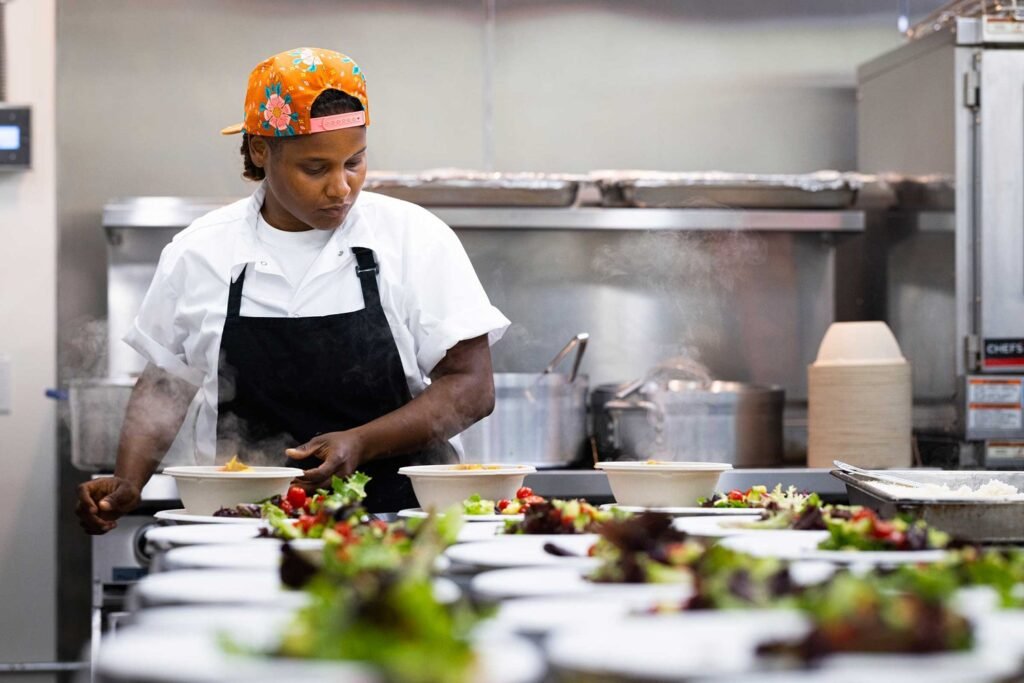 Chef Chantelle Sookram plating a row of salads on the pass