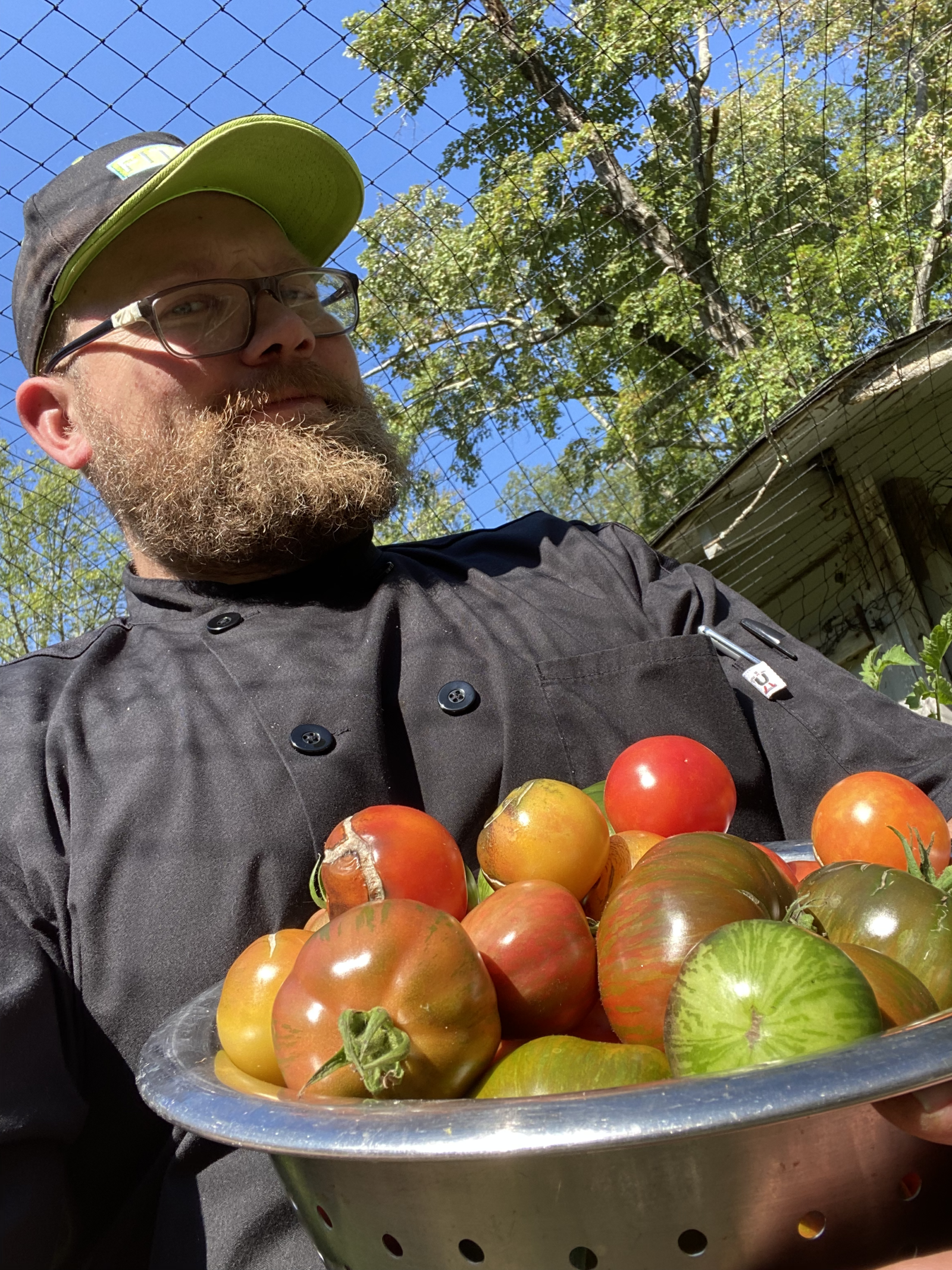 Chef Keith Kalmanowicz holding a colander of heirloom tomatoes