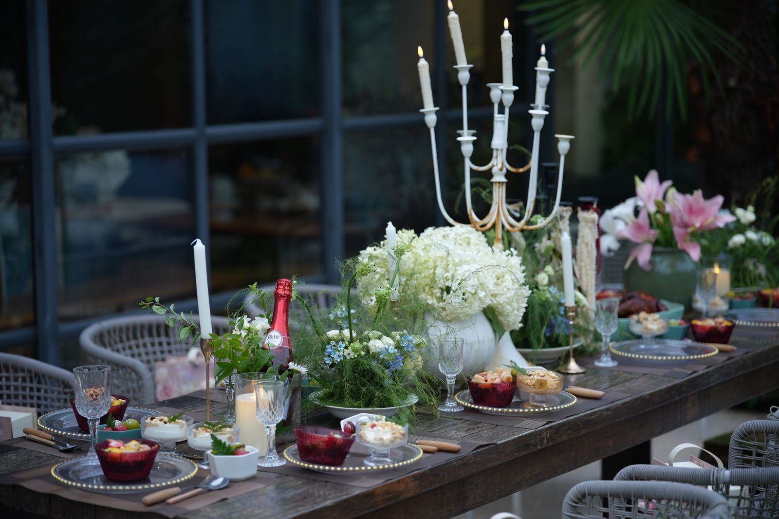 A long table set with candles and greenery for an outdoor dinner
